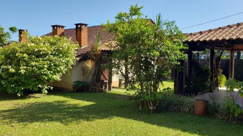 a house with a yard with bushes and trees at Pousada Atelier Aly da Costa in Iguape