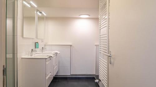 a white bathroom with a sink and a mirror at Duinlust Dishoek in Dishoek