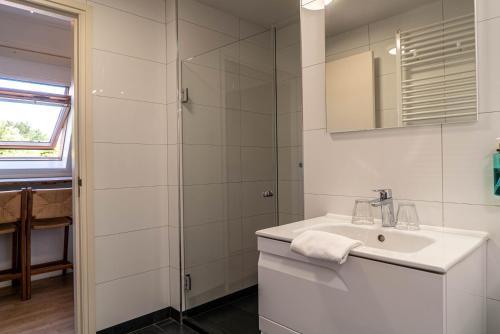 a white bathroom with a sink and a shower at Duinlust Dishoek in Dishoek