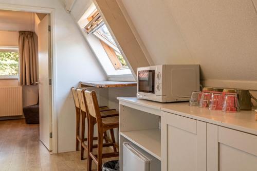 a kitchen with a microwave on a counter with chairs at Duinlust Dishoek in Dishoek