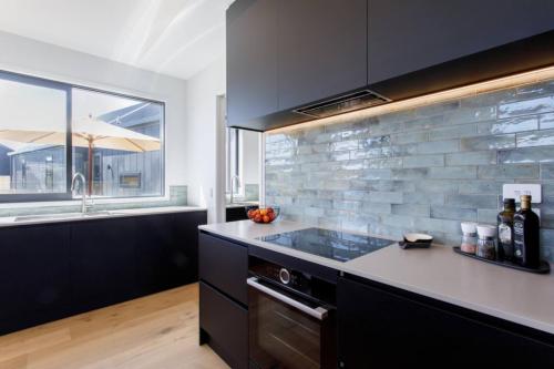 a kitchen with black cabinets and a counter top at Prowess Lodge luxury accommodation with private pool and spa in Wanaka