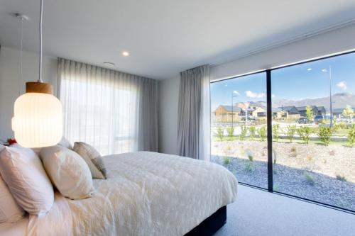 a bedroom with a bed and a large window at Prowess Lodge luxury accommodation with private pool and spa in Wanaka