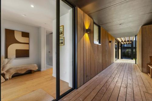 a hallway of a house with wooden flooring and glass walls at Alpine Hideaway Eco Retreat in Wanaka