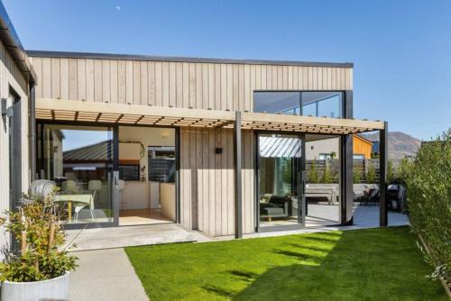 a modern house with glass doors and a lawn at Alpine Hideaway Eco Retreat in Wanaka