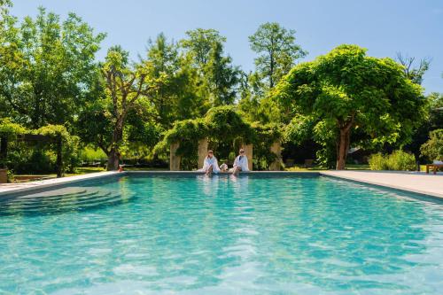 two people sitting on the edge of a swimming pool at Chateau De Germigney in Port-Lesney