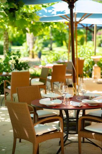 a table and chairs with wine glasses and an umbrella at Chateau De Germigney in Port-Lesney