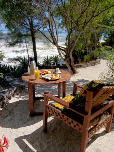 a table with a plate of food and a chair at AFYA Village at the sea in Michamvi