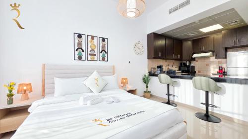 a bedroom with a large white bed and a kitchen at Hydra C6 Studio - Luxe View Retreat in Abu Dhabi