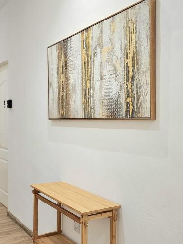 a painting hanging on a wall with a wooden table at Luna Suites Comfort Stay in Lahad Datu in Lahad Datu