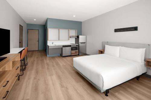 a bedroom with a large white bed and a kitchen at StudioRes Fort Myers in Fort Myers