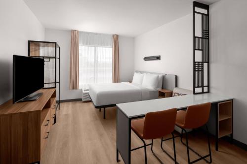 a hotel room with a bed and a table and chairs at StudioRes Fort Myers in Fort Myers