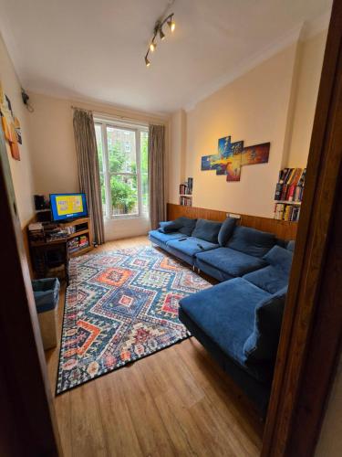 a living room with a blue couch and a rug at Barmy Badger Backpackers in London