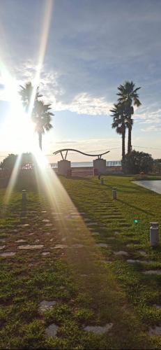 a sun shining on a grass field with palm trees at Tale Sunset Apartament in Lezhë