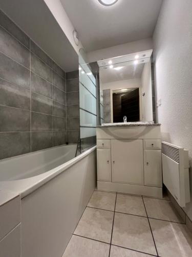 Un baño con bañera, lavabo y espejo. en Loc luz st sauveur 6, en Luz-Saint-Sauveur