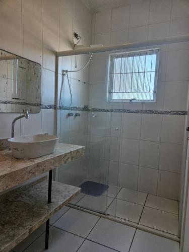 a bathroom with a sink and a shower at Relaxe num sobrado com piscina in Peruíbe