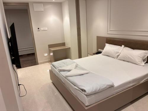 a bedroom with a bed with white sheets and a television at Swarn Hotel in Kolkata