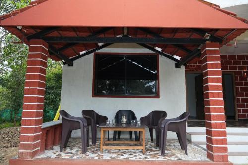 a patio with a table and chairs under a red roof at Garcinia Villa in Sirsi