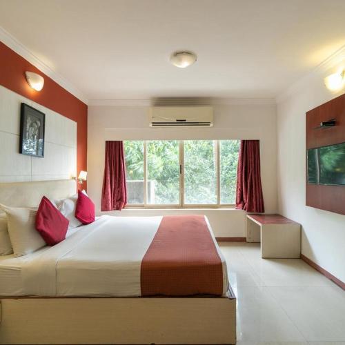 a bedroom with a large bed with red walls at Presidency Landmark in Daman