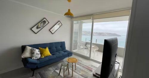 a living room with a blue couch and a television at Frente al mar primera linea in Coquimbo