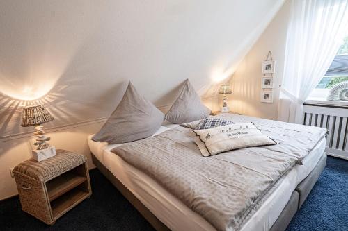 ビューズムにあるHaus Hollmannの白いシーツと枕が備わったベッドのある寝室
