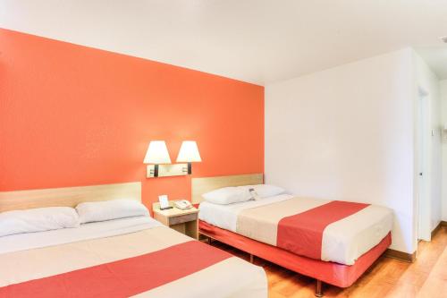 two beds in a room with orange walls at Motel 6-Tigard, OR - Portland South - Lake Oswego in Tigard