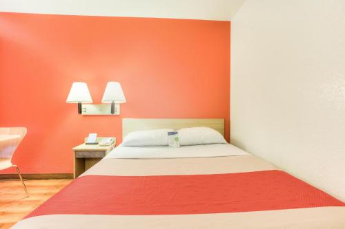 a bedroom with a bed and a red wall at Motel 6-Tigard, OR - Portland South - Lake Oswego in Tigard