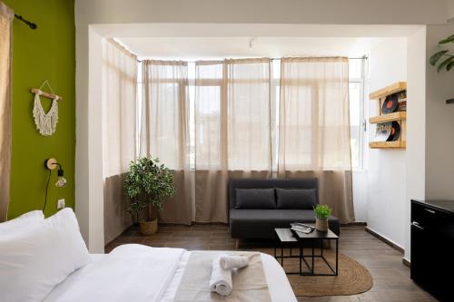 a bedroom with a bed and a chair and a window at Rena's House - Beach Edition in Tel Aviv