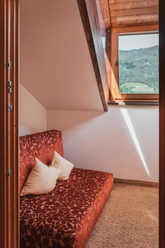 a red couch in a room with a window at Hotel Traube in Bressanone