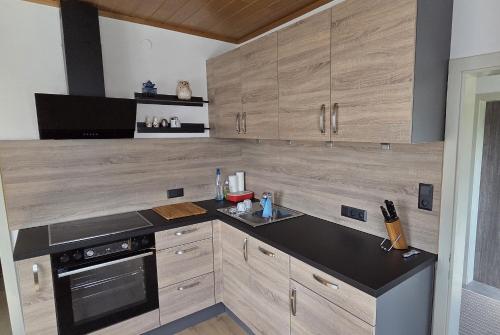 a kitchen with wooden cabinets and a black counter top at Ferienhaus Ofenluger in idylischer Lage inkl Garage und Griller in Fischbach
