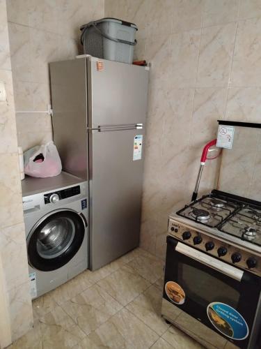 Una cocina con estufa, refrigerador y lavadora. en العقبة, en Áqaba