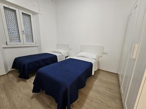 zwei Betten in einem weißen Zimmer mit blauen Laken in der Unterkunft Dream & Fly Centrale in Fiumicino