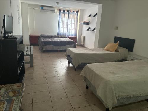 Una habitación de hotel con tres camas y un televisor de pantalla plana. en Belgrano 10, en Salta