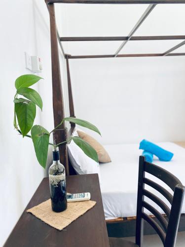 a table with a bottle and a plant on it at White Resort - 1 Min walk to the Beaches in Tangalle