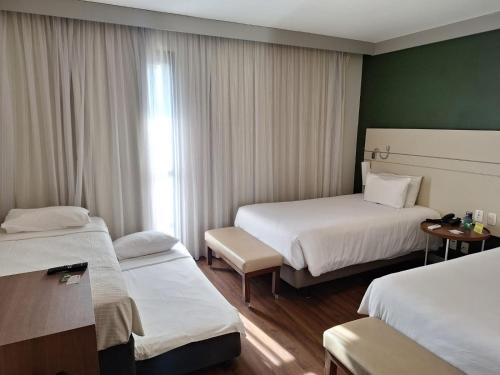 a hotel room with two beds and a window at Quality Faria Lima in Sao Paulo