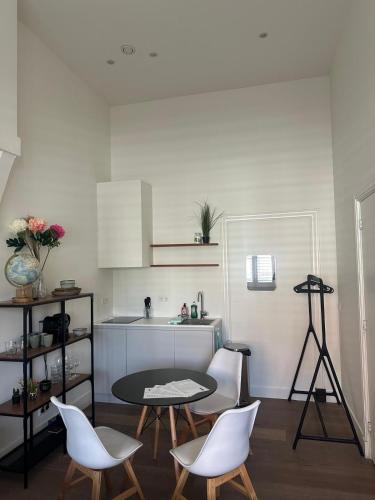 a kitchen with a table and white chairs and a table at Comfortable City Break Studio in The Hague