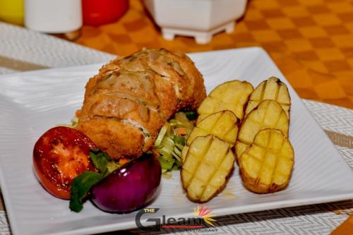 a white plate with a sandwich and french fries at The Gleam Hotel in Mai Mahoro