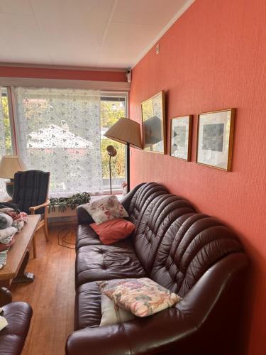 a leather couch in a living room with red walls at Asleep in the Valley Villa in Oslo