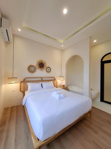 a bedroom with a large white bed and a bath tub at Cerita Kita Villa by Staycation Villa Jogja in Jetis