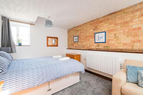 a bedroom with a bed and a brick wall at Cottage 4 at Scald end in Bedford