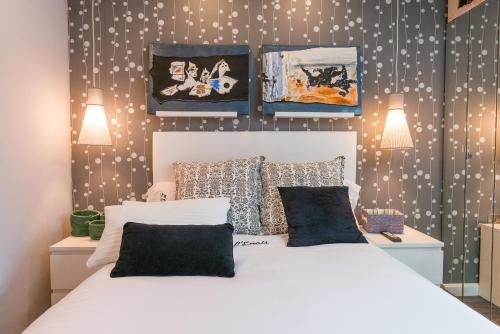 a bedroom with a white bed and some pictures on the wall at L'encis apartament in Muros de Nalón