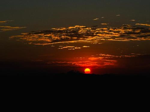an orange sunset in the sky with clouds at Cabana Teixeira in Cunha