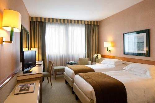 a hotel room with two beds and a television at Starhotels President in Genova