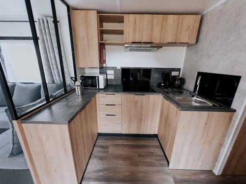 a small kitchen with wooden cabinets and a sink at Zeehuisje Naija in Renesse