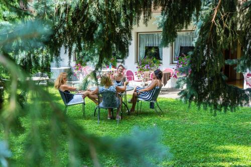 a group of women sitting around a table in a yard at Hotel Pension Schweitzer in Silandro