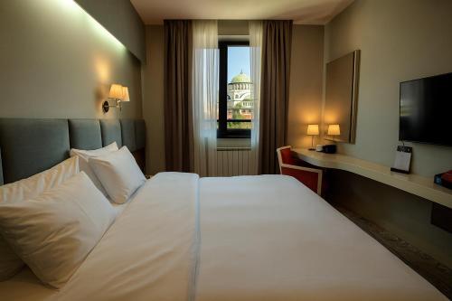 a hotel room with a large white bed and a window at CRYSTAL Hotel Belgrade in Belgrade