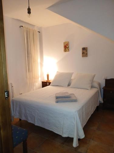 a bedroom with a white bed with towels on it at Encanto del Gregorio in Huerta del Marquesado
