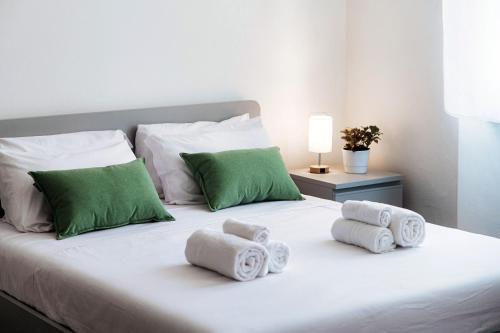 a white bed with green pillows and towels on it at Casa Batèl Suites & Apartments - By Breva Collections in Como