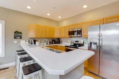 a kitchen with wooden cabinets and stainless steel refrigerator at Less Than Half-Mi to Lake Townhome with Hot Tub in McHenry! in McHenry