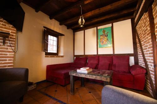 a living room with a red couch and a table at Las Casas del Nogal - Guesthouse en Sierra Nevada in Güéjar-Sierra