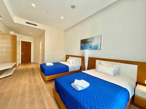 two beds in a hotel room with blue sheets at Condo Studio Plaza in Budva